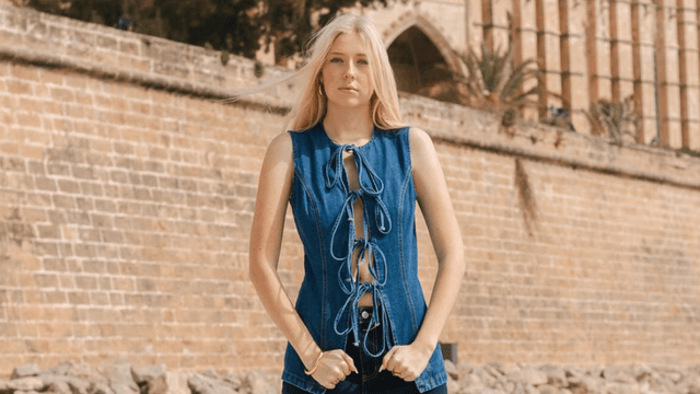 Emilia Knudsen wearing a blue lace-up denim top in front of a historic stone building.