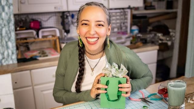 Brittany Arnett, founder of The Dappled Wood, holding a green gift bag with nature-inspired earrings.