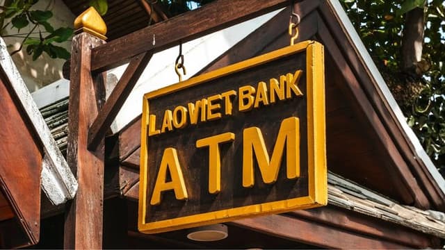 an ATM sign from LaoViet Bank, highlighting the importance of avoiding high ATM fees while traveling abroad.