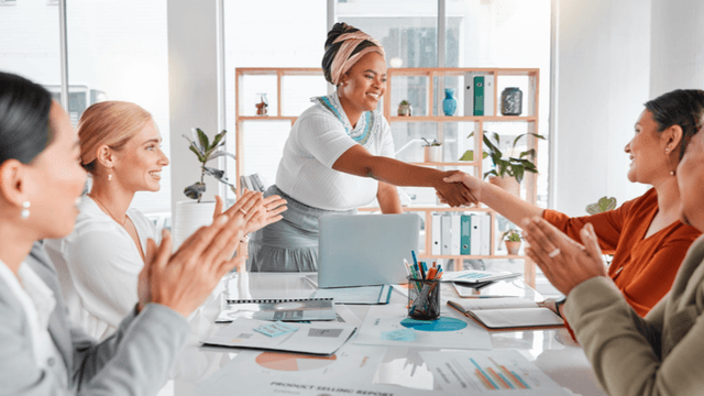 "Dr. Rita Reneé leading a business meeting with women, fostering empowerment, collaboration, and feminine leadership in a professional setting."
