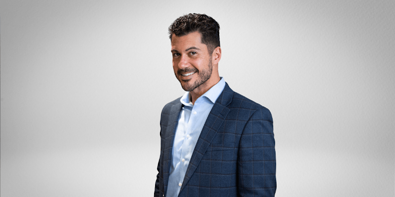 A smiling man in a business suit against a simple background