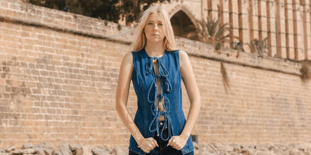 Emilia Knudsen wearing a blue lace-up denim top in front of a historic stone building.