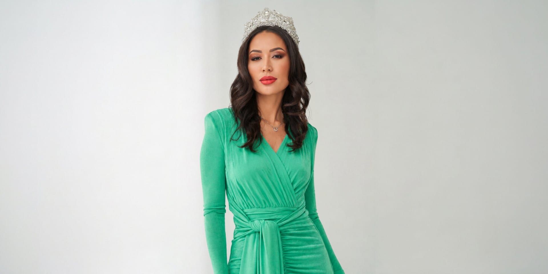 Aika Iskakova wearing a green gown and crown during a formal portrait.