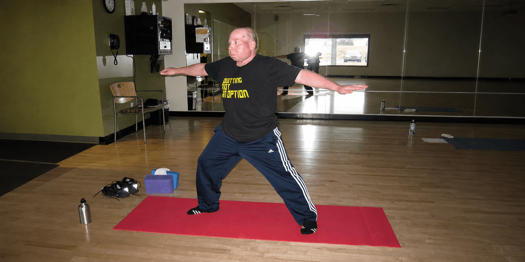 Person practicing a yoga pose on a red mat in a fitness studio.
