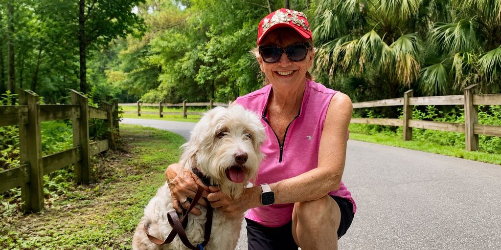 Stacey Bonner with Daisy the Doodle on a wooded walking trail in Florida.