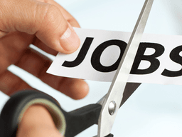 A hand using scissors to cut a paper with the word "JOBS" on it
