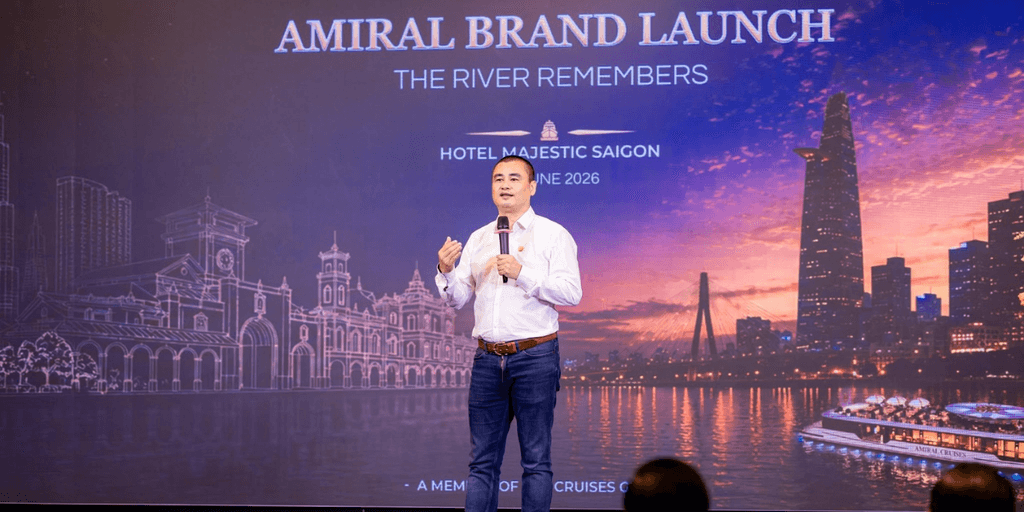 A speaker presenting at the Amiral brand launch event in front of a city skyline backdrop