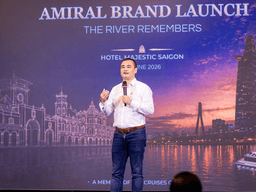 A speaker presenting at the Amiral brand launch event in front of a city skyline backdrop