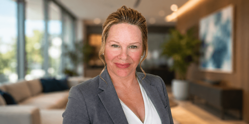 Professional woman in a gray blazer smiling in a modern office setting