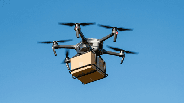 Drone carrying a cardboard box against a clear blue sky