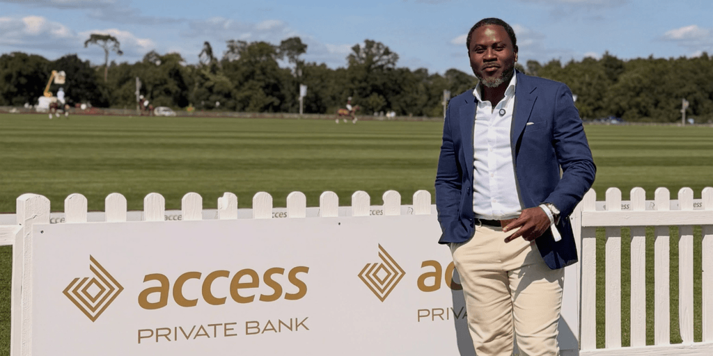 Man in a blue blazer and beige pants poses beside Access Private Bank sign
