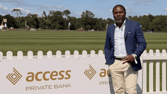 Man in a blue blazer and beige pants poses beside Access Private Bank sign