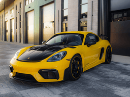 A yellow Porsche 718 GT4 parked in front of a modern garage.