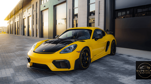 A yellow Porsche 718 GT4 parked in front of a modern garage.