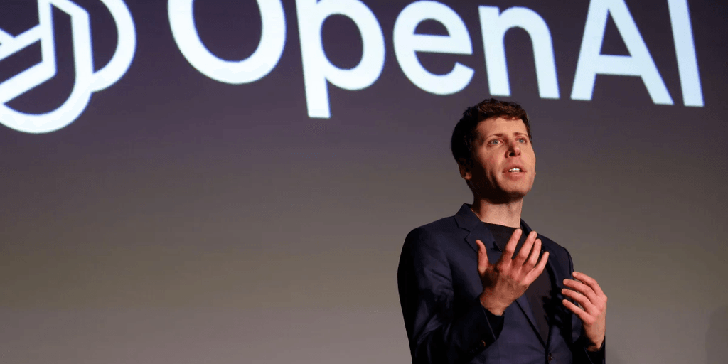 Person speaking on stage with OpenAI logo in the background