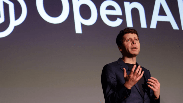 Person speaking on stage with OpenAI logo in the background