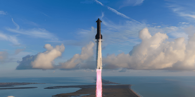 A rocket launches into a clear sky over a coastal landscape with clouds