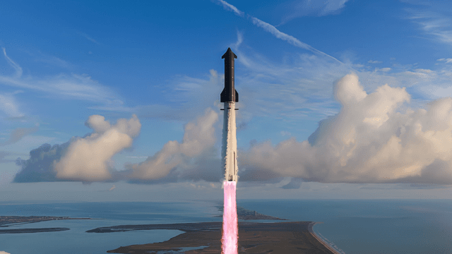 A rocket launches into a clear sky over a coastal landscape with clouds