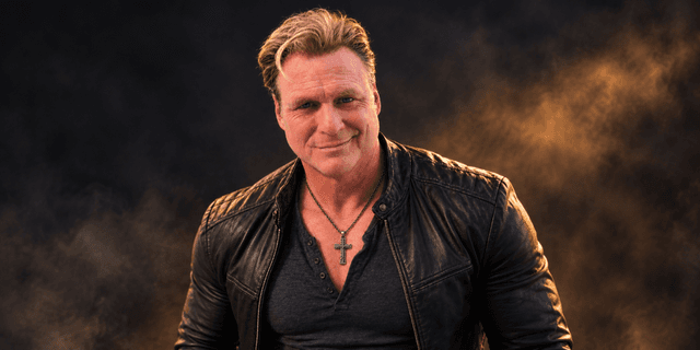 Man in a leather jacket poses confidently with a smoky background