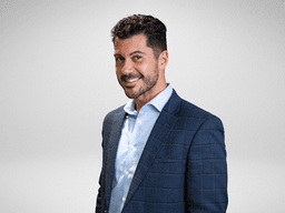 A smiling man in a business suit against a simple background