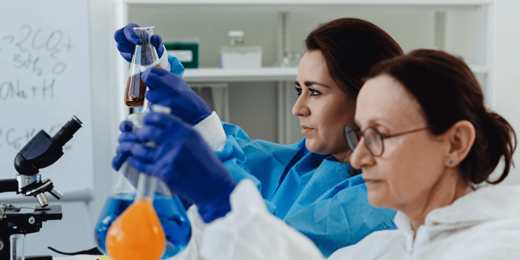 Two scientists in lab coats conduct experiments with colorful liquid in flasks