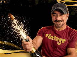 Smiling man in a cap opening champagne with sparkling bubbles around him