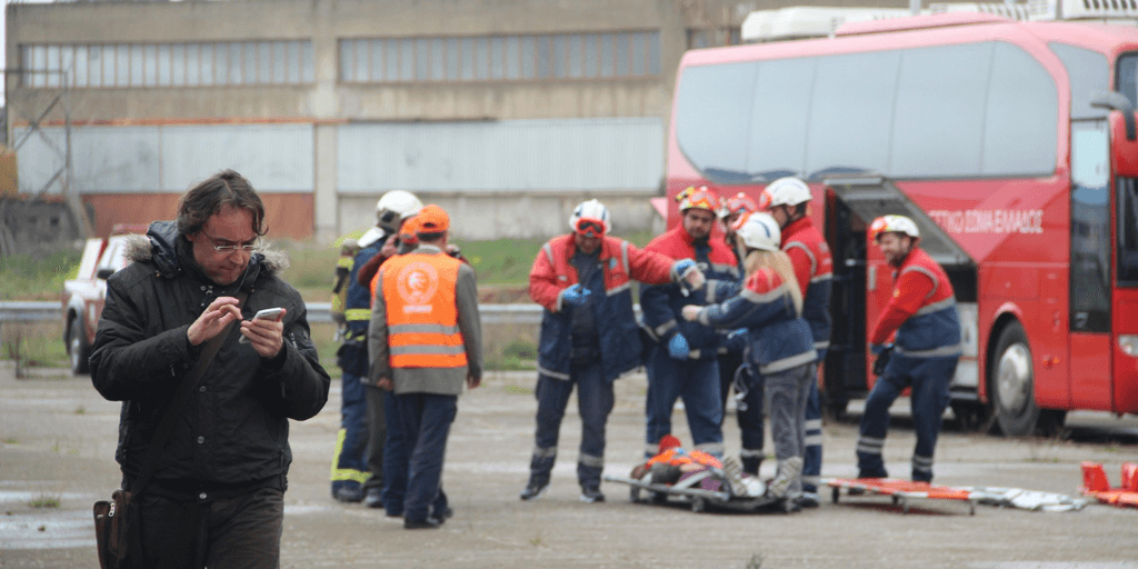 Rescue workers prepare gear while a man checks his phone nearby.