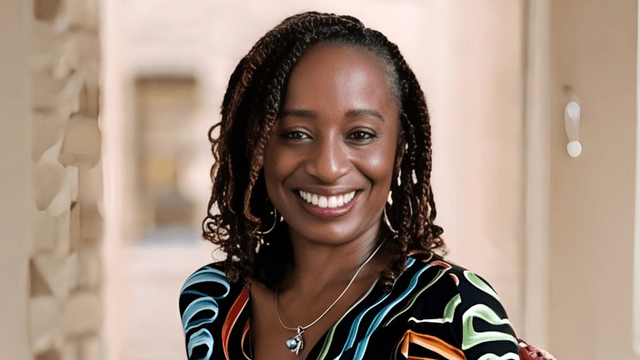 Illyasha Peete smiling confidently, wearing a colorful shirt, with a soft background.