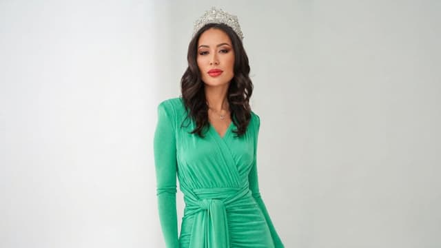 Aika Iskakova wearing a green gown and crown during a formal portrait.