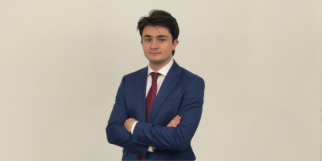 Marcos Agustín, in a blue suit and white shirt, embodies the vision of OpenMacro for accessible global macro investing.