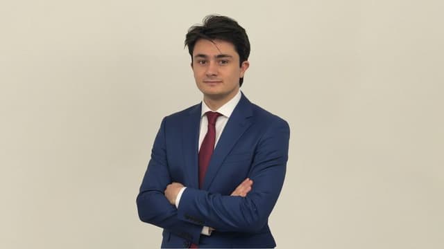 Marcos Agustín, in a blue suit and white shirt, embodies the vision of OpenMacro for accessible global macro investing.