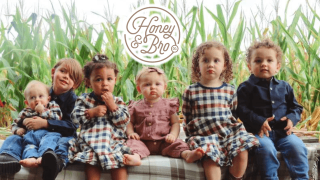 Six children dressed in cozy, eco-friendly outfits from Honey and Bro Co., seated together with a cornfield backdrop.