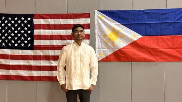 Ranell Engay stands proudly between the American and Philippine flags, symbolizing his global impact in science education.