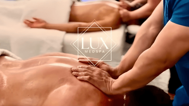 Massage therapist applying oil to client's back at Lux MedSpa treatment room.