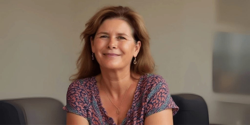Helena Demuynck smiling in an office, empowering women leaders through authentic, conscious leadership and transformation coaching.
