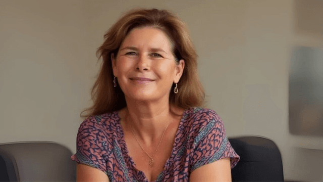 Helena Demuynck smiling in an office, empowering women leaders through authentic, conscious leadership and transformation coaching.