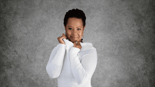 Mag Dalé posing confidently in a white sweater, radiating warmth and strength.