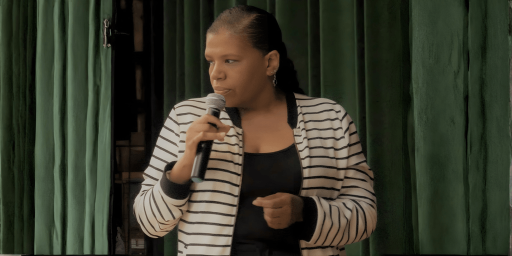 Jillian Bullock speaking into a microphone, sharing her story of resilience and transformation.