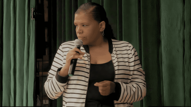 Jillian Bullock speaking into a microphone, sharing her story of resilience and transformation.