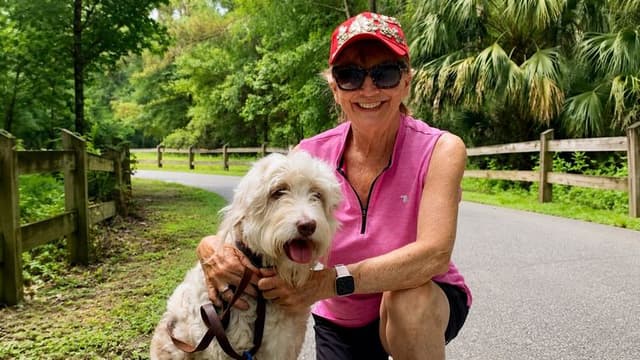 Stacey Bonner with Daisy the Doodle on a wooded walking trail in Florida.