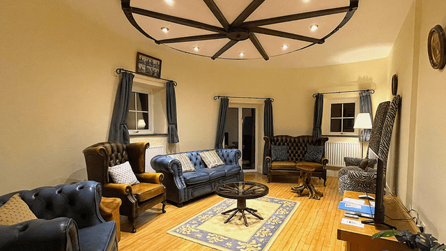"Cozy living room in a windmill, featuring luxurious leather chairs, a unique ceiling light fixture, and a patterned rug."
