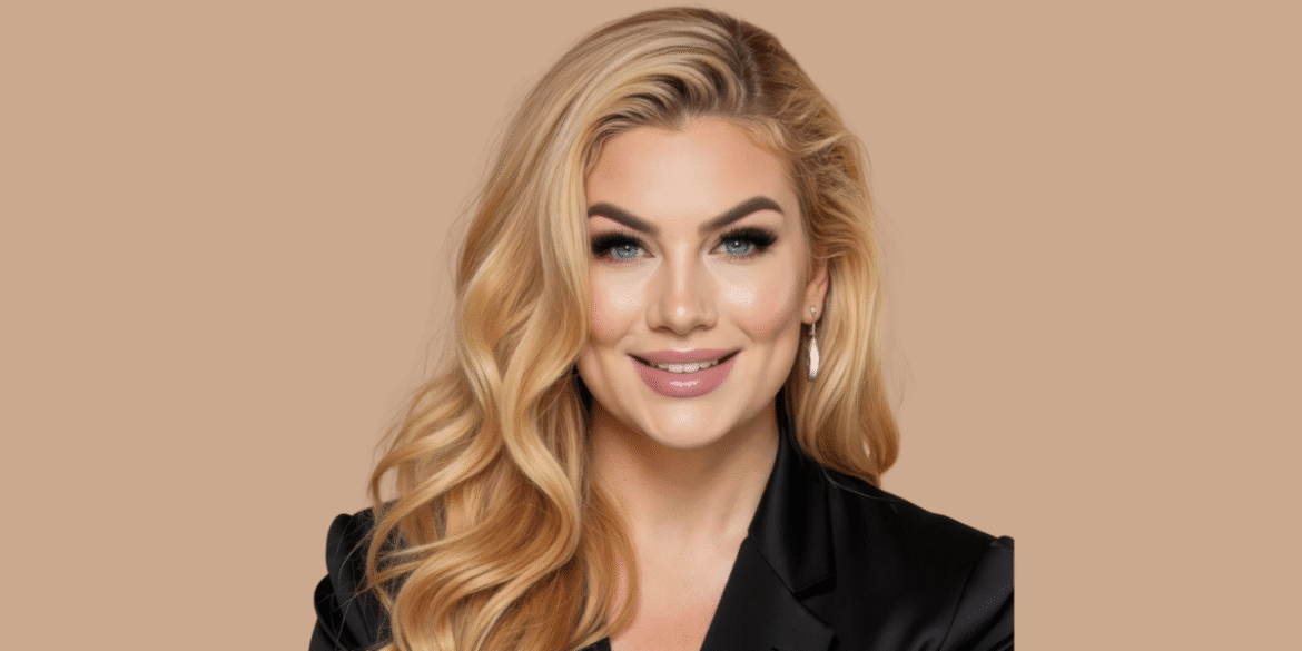 Portrait of a confident blonde woman with soft waves, wearing a black blazer and minimal makeup, smiling against a beige background.