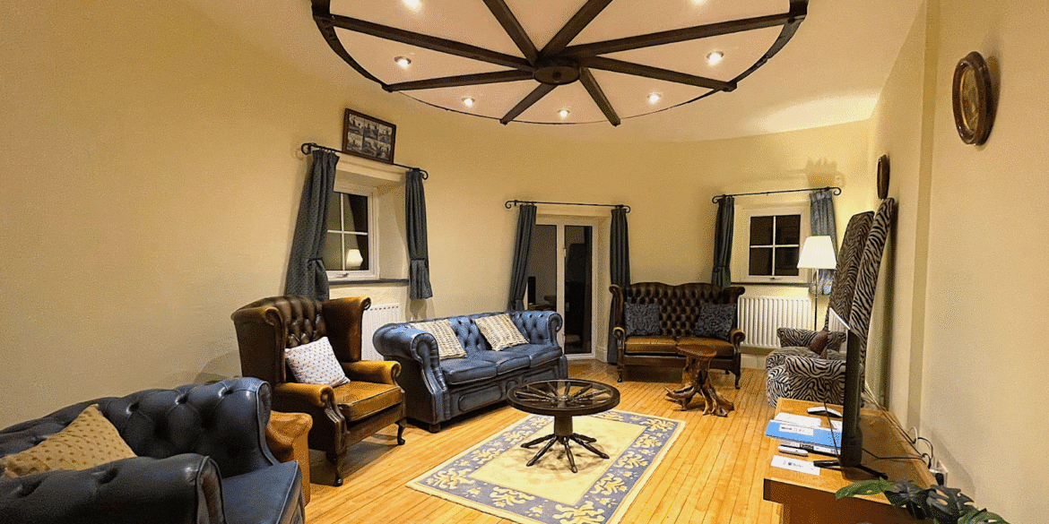 "Cozy living room in a windmill, featuring luxurious leather chairs, a unique ceiling light fixture, and a patterned rug."
