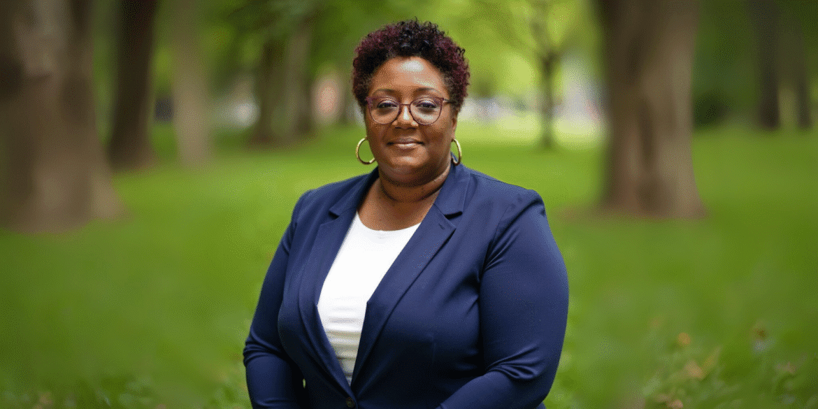 Rosalyn Casas stands outdoors in a navy blazer, smiling confidently with trees and greenery in the background.