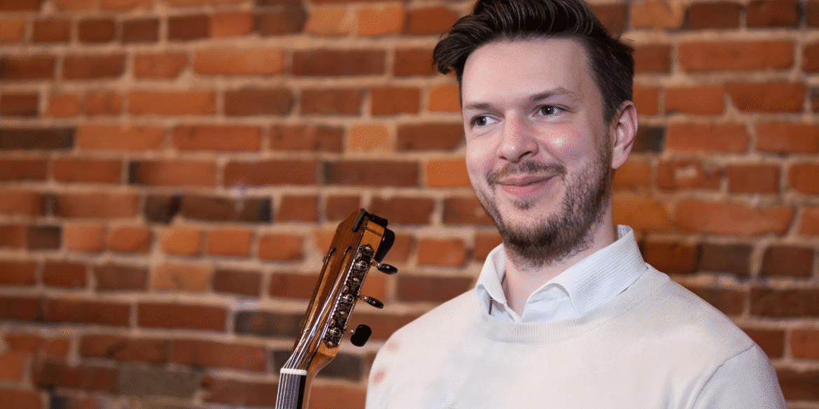 "Troy Serson, guitar instructor, smiling with guitar in hand, offering personalized, online lessons to students of all ages."