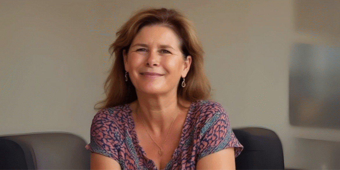 Helena Demuynck smiling in an office, empowering women leaders through authentic, conscious leadership and transformation coaching.