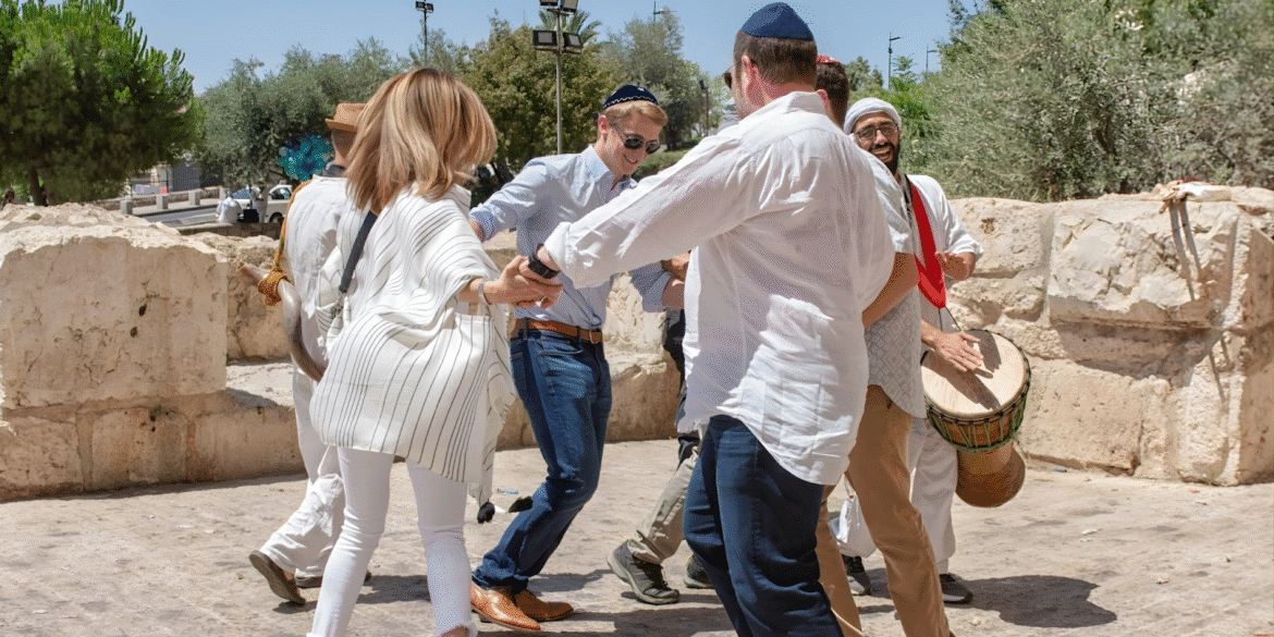 People dancing joyfully during a Bar Mitzvah celebration in Israel with live music and traditional dress.