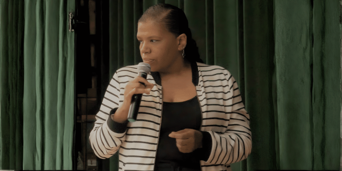 Jillian Bullock speaking into a microphone, sharing her story of resilience and transformation.