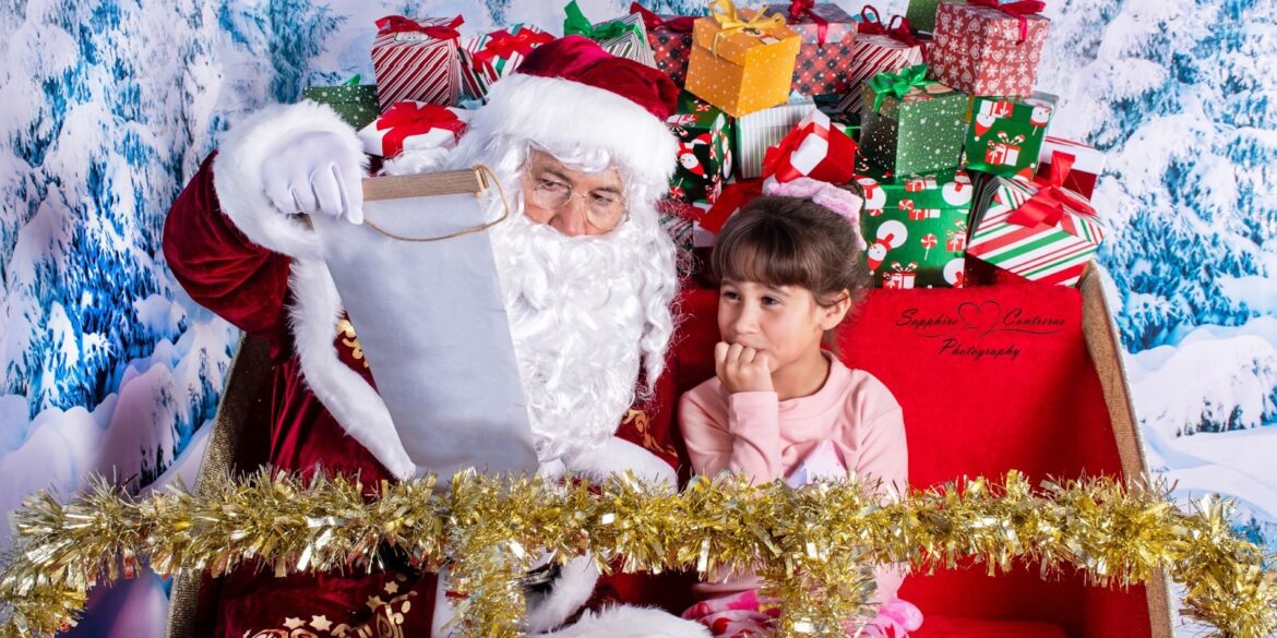 A joyful holiday photo with Santa and a young girl, surrounded by Christmas gifts, capturing a special moment.