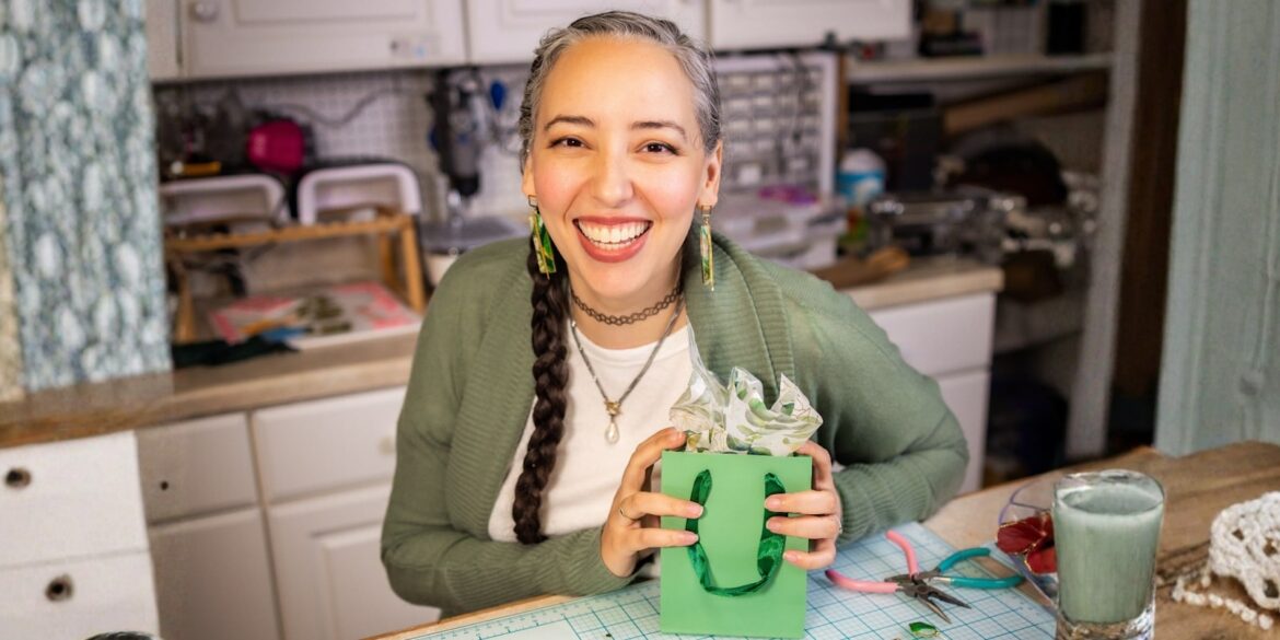 Brittany Arnett, founder of The Dappled Wood, holding a green gift bag with nature-inspired earrings.